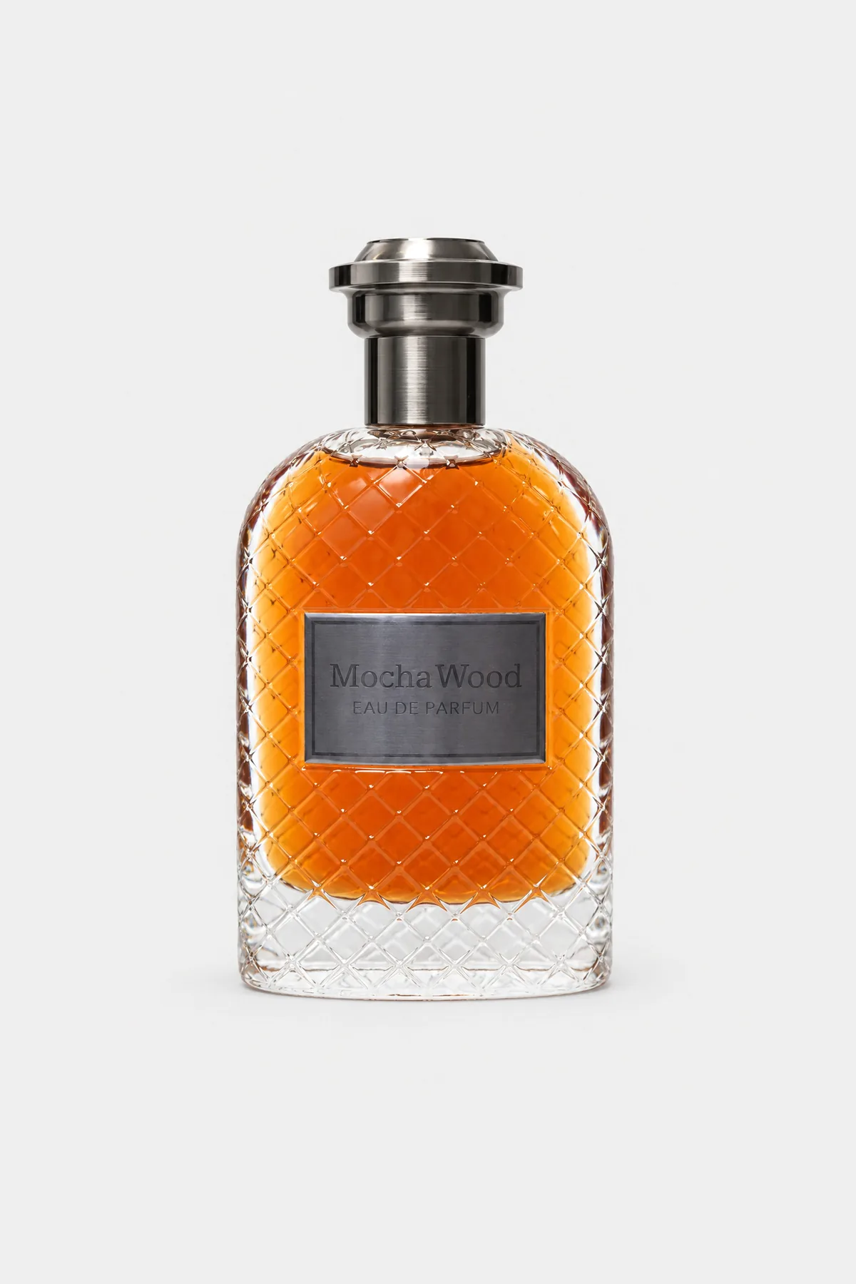 Fragrance World Mocha Wood Eau de Parfum 100 ml, diamond-cut glass with amber liquid, gunmetal cap and dark plate, front view